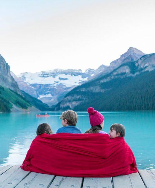 4 kids sitting on a dock at Lake Louise in Banff National Park in Alberta Canada