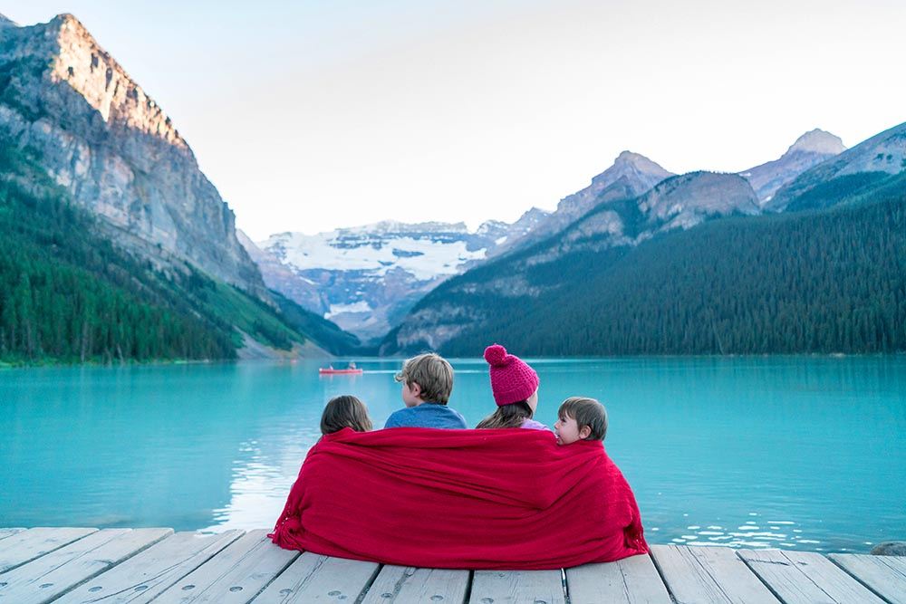 4 kids sitting on a dock at Lake Louise in Banff National Park in Alberta Canada