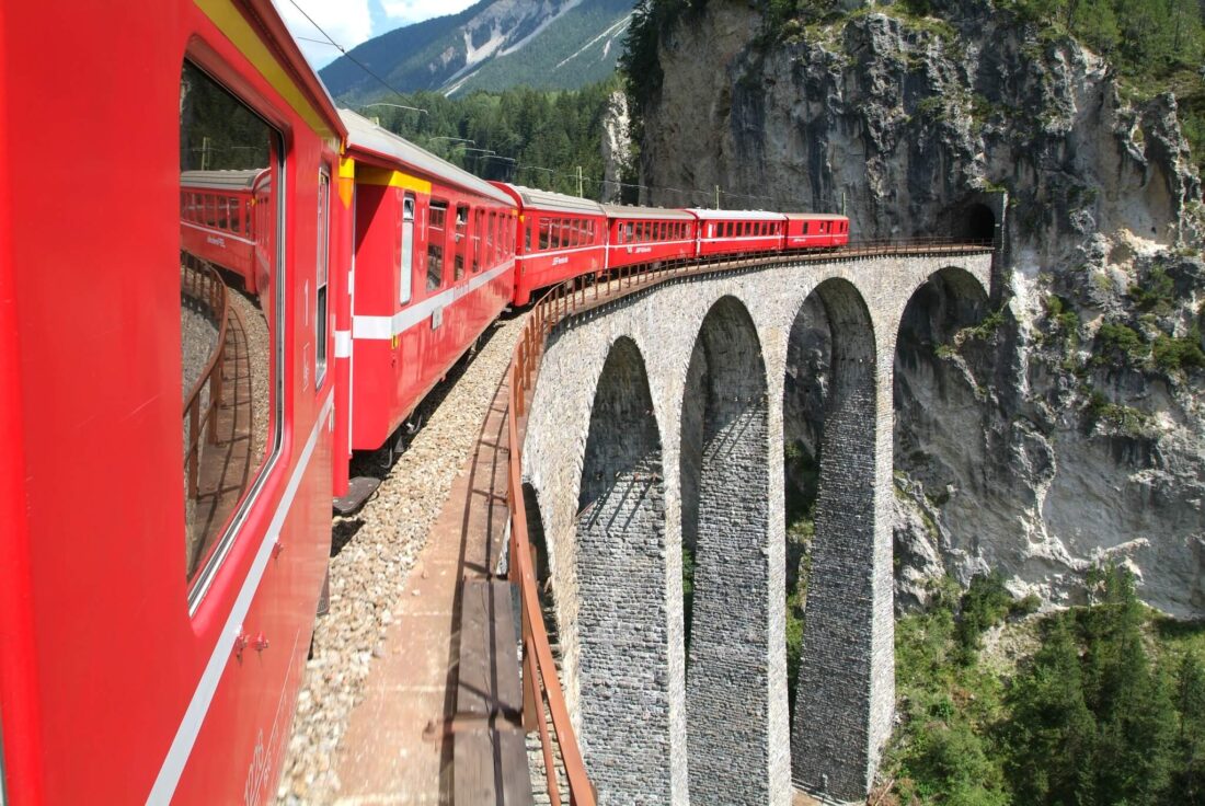 A red train going into a tunnel in a mountain in Switzerland
