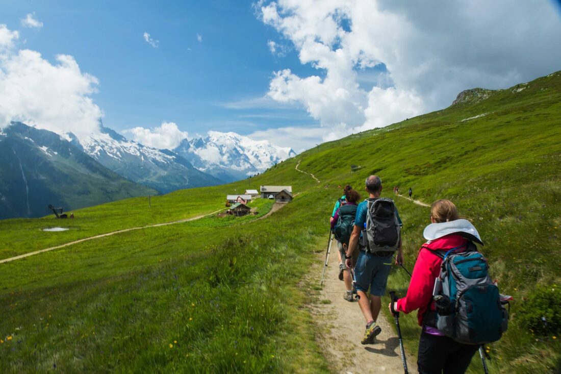 A group of people hiking through the alps in Switzerland with hiking poles and backpacks