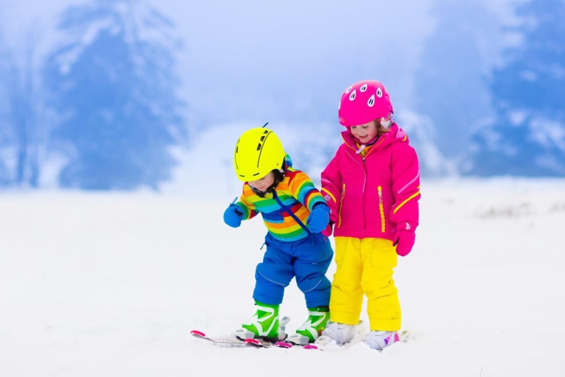 Two kids skiing in bright clothing in Switzerland