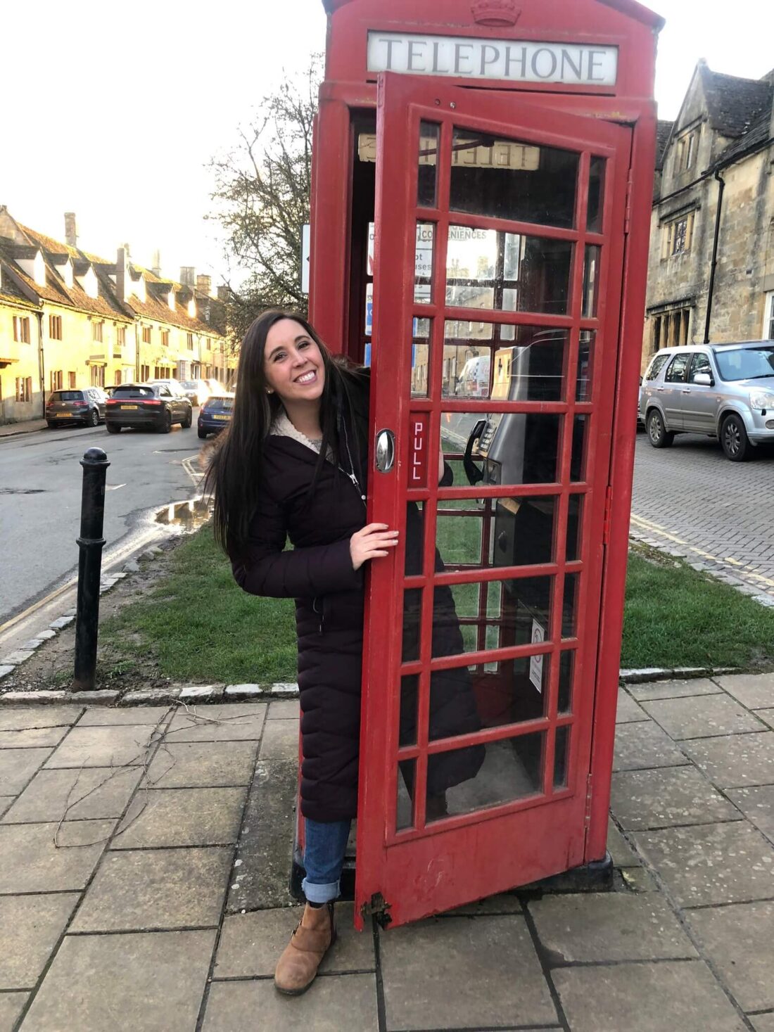 Most Beautiful Cotswolds Villages - a woman standing in a red telephone booth in broadway