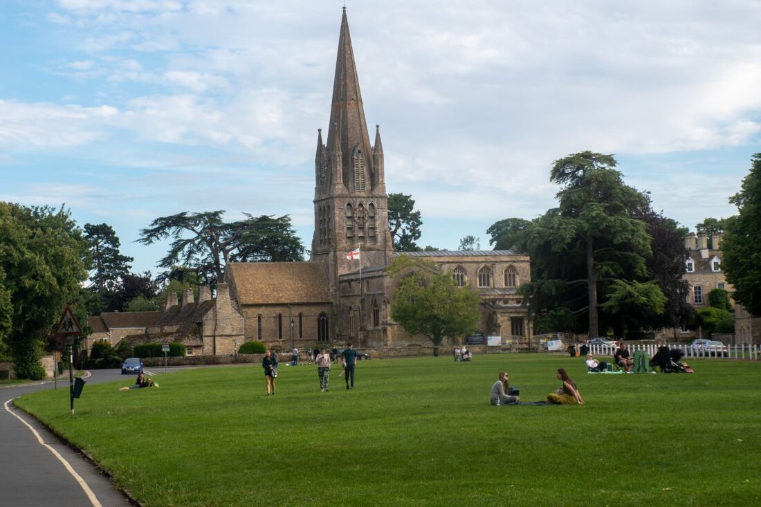 Most Beautiful Cotswolds Villages - 
town square and chrch in Witney with people sitting on the lawn